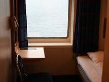 Inside a cabin onboard Mecklenburg with a bed and table